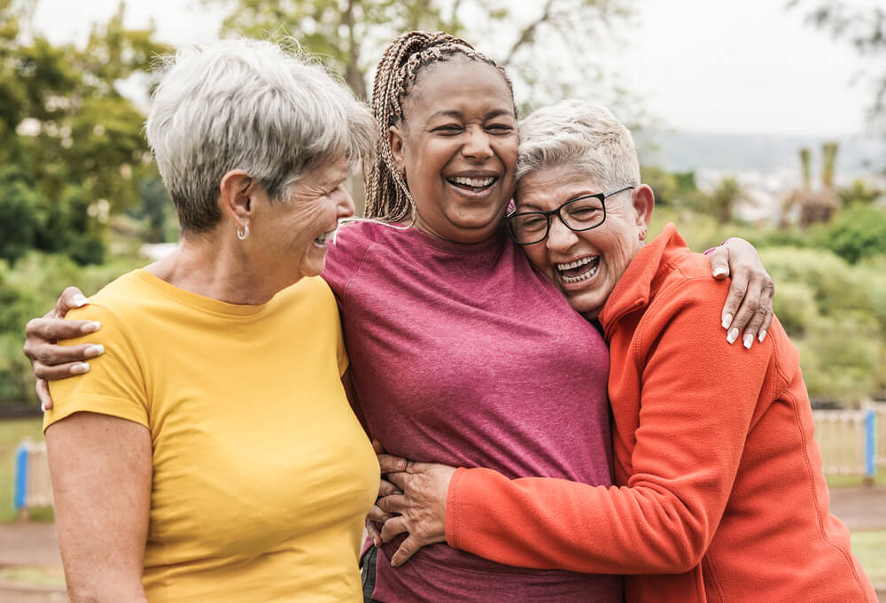 Three senior women hugging and laughing