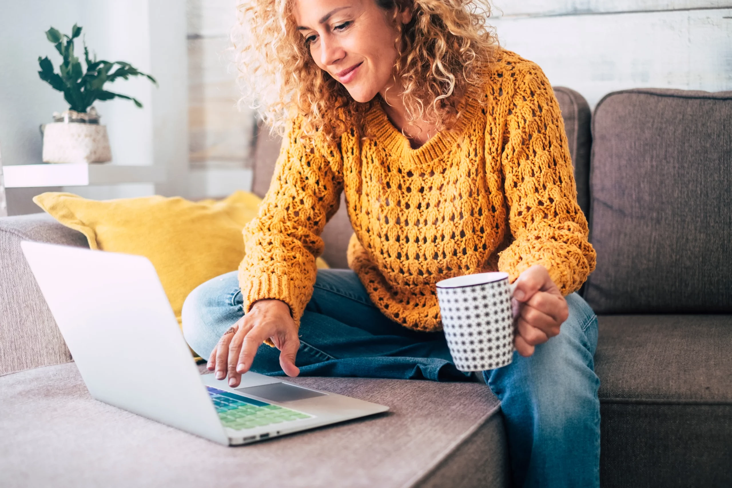 women holding a coffee mug scrolling on her laptop